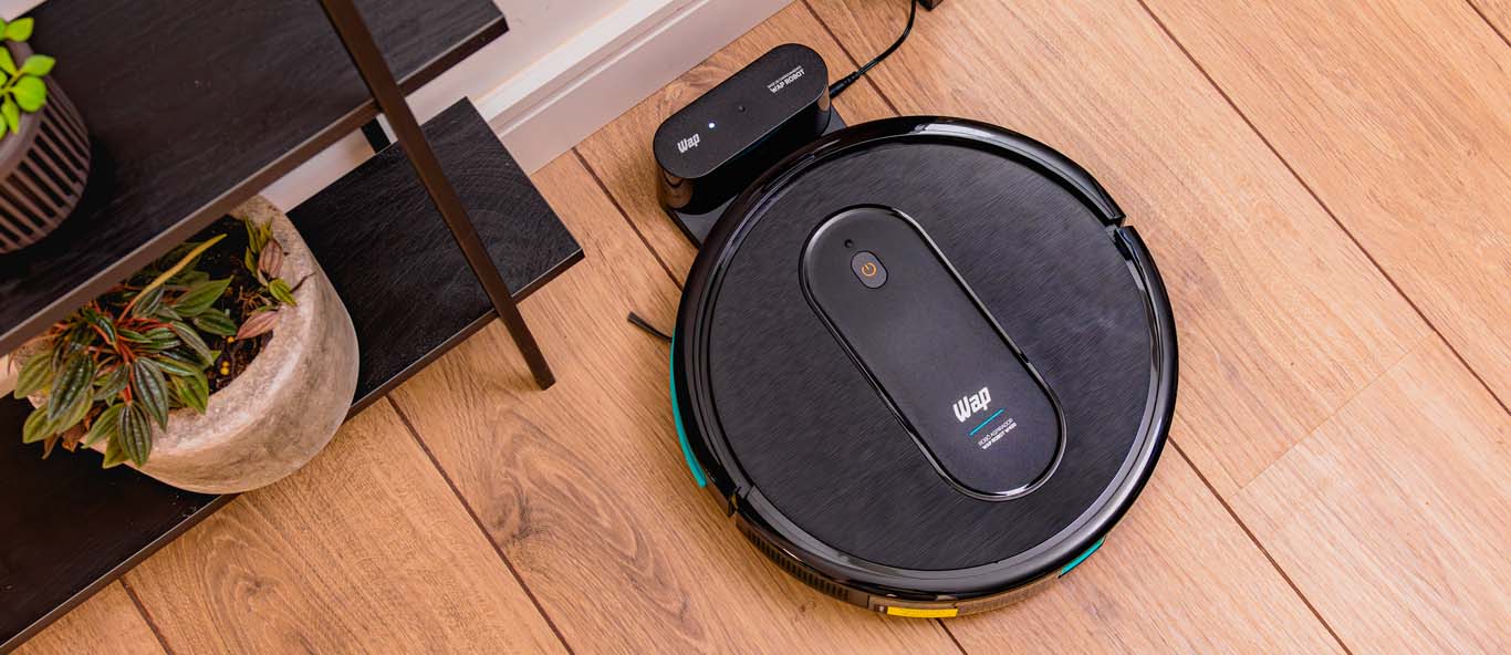 Robô aspirador WAP Robot W400 preto sobre piso de madeira ao lado da base de recarga